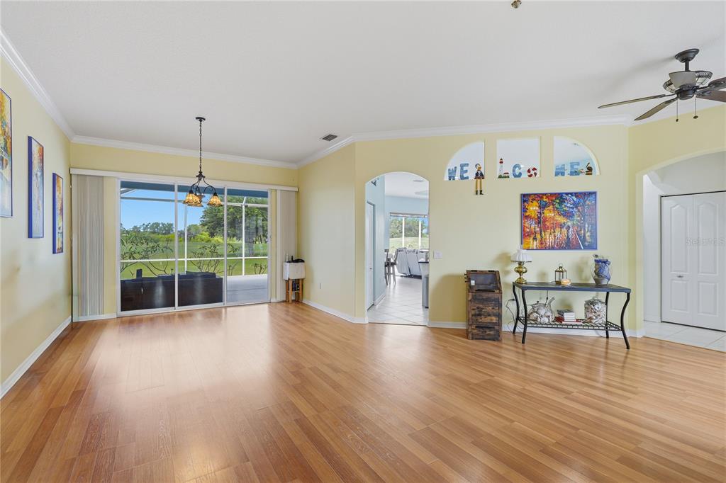 A spacious living area with light yellow walls, wood flooring, and a sliding glass door — 758 PLANTERS MANOR WAY, BRADENTON, FL