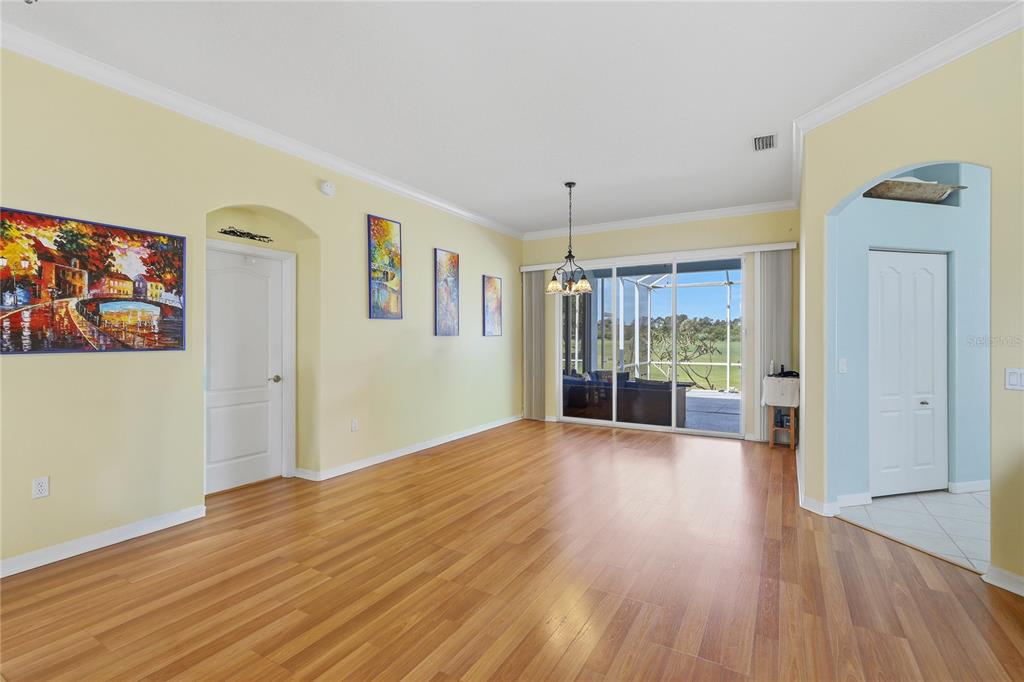 A spacious living room features light yellow walls, wood-look flooring, and sliding glass doors — 758 PLANTERS MANOR WAY, BRADENTON, FL