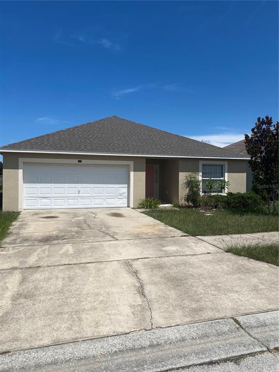 A single-story house with a beige exterior, a two-car garage, and a concrete driveway — 135 STEWART LAKE LOOP, GROVELAND, FL