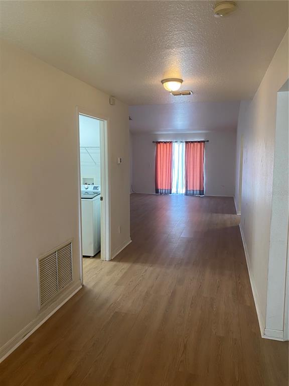 A hallway with light wood-look flooring leads to a living area with orange curtains — 135 STEWART LAKE LOOP, GROVELAND, FL