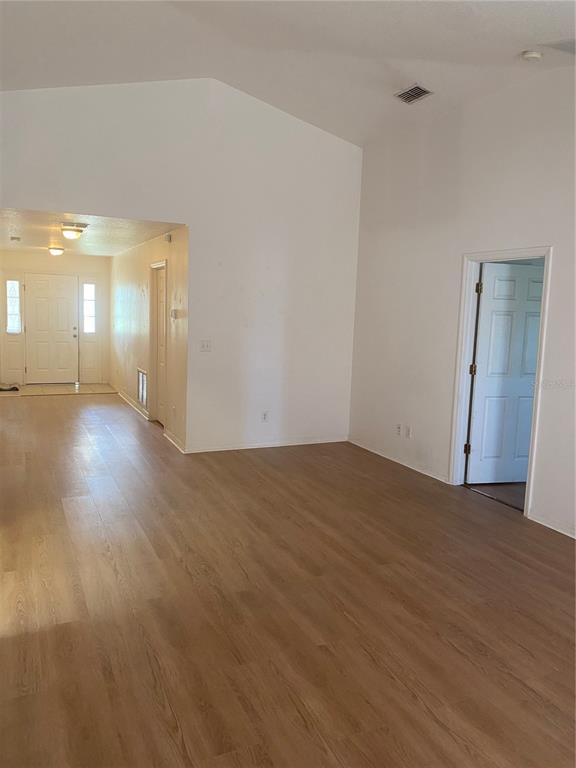 An interior view shows a living area with light wood-look flooring and vaulted ceilings — 135 STEWART LAKE LOOP, GROVELAND, FL