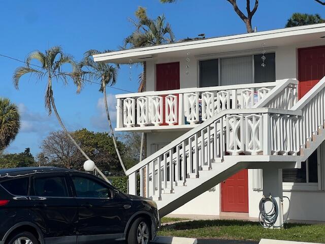 A two-story white apartment building features red doors, a white balcony railing, and exterior stairs — 2020 Lake Osborne Drive # 11, FL 33461, FL