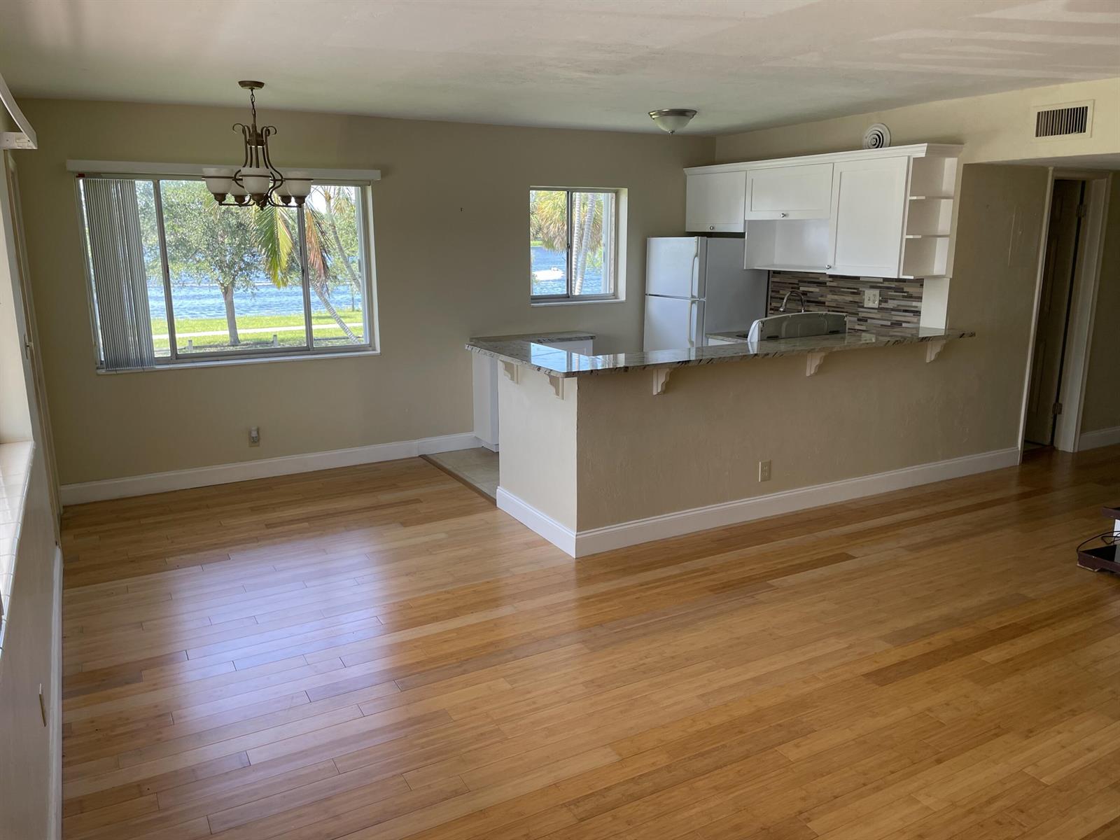 A dining area and kitchen with a breakfast bar, wood flooring, and a water view — 2020 Lake Osborne Drive # 11, FL 33461, FL