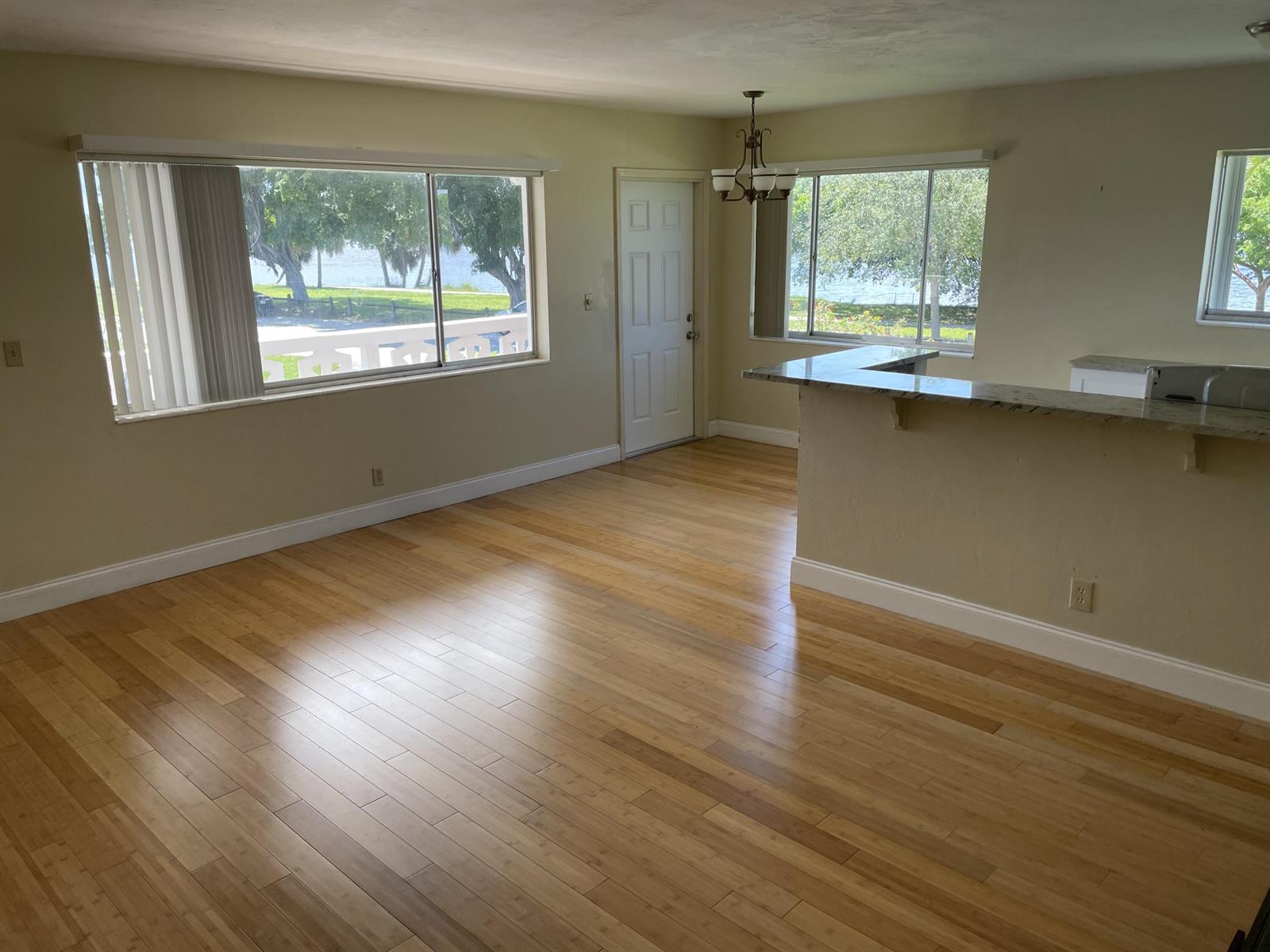 An open living area features light wood flooring, a breakfast bar, and large windows overlooking water — 2020 Lake Osborne Drive # 11, FL 33461, FL