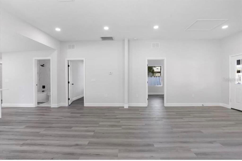 A bright, open-concept room features light gray wood-look flooring, recessed lighting, and three doorways — 506 N WARNELL STREET, PLANT CITY, FL