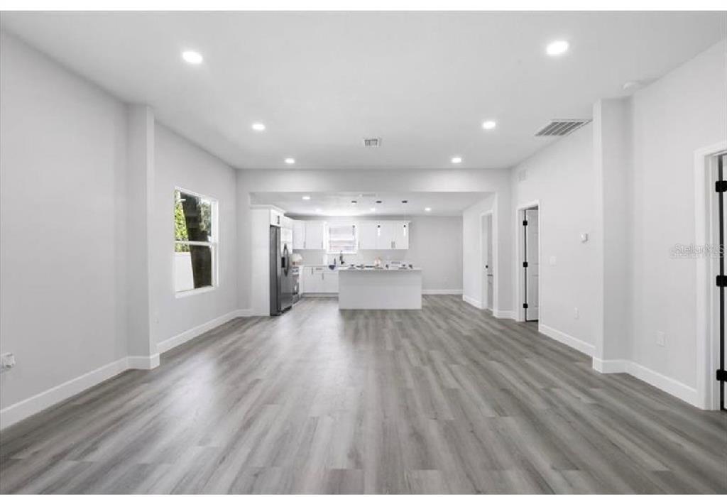 An open-concept living area features light gray walls, wood-look flooring, and a white kitchen island — 506 N WARNELL STREET, PLANT CITY, FL