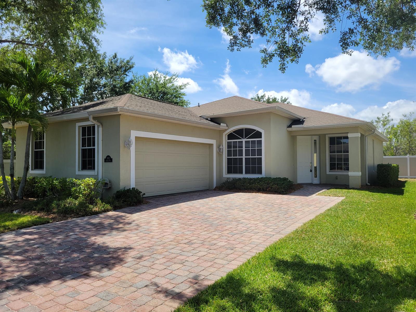 A single-story house with a beige stucco exterior, a paver driveway, and a two-car garage — 3103 Anthem Way, Vero Beach FL 32966, VERO BEACH, FL