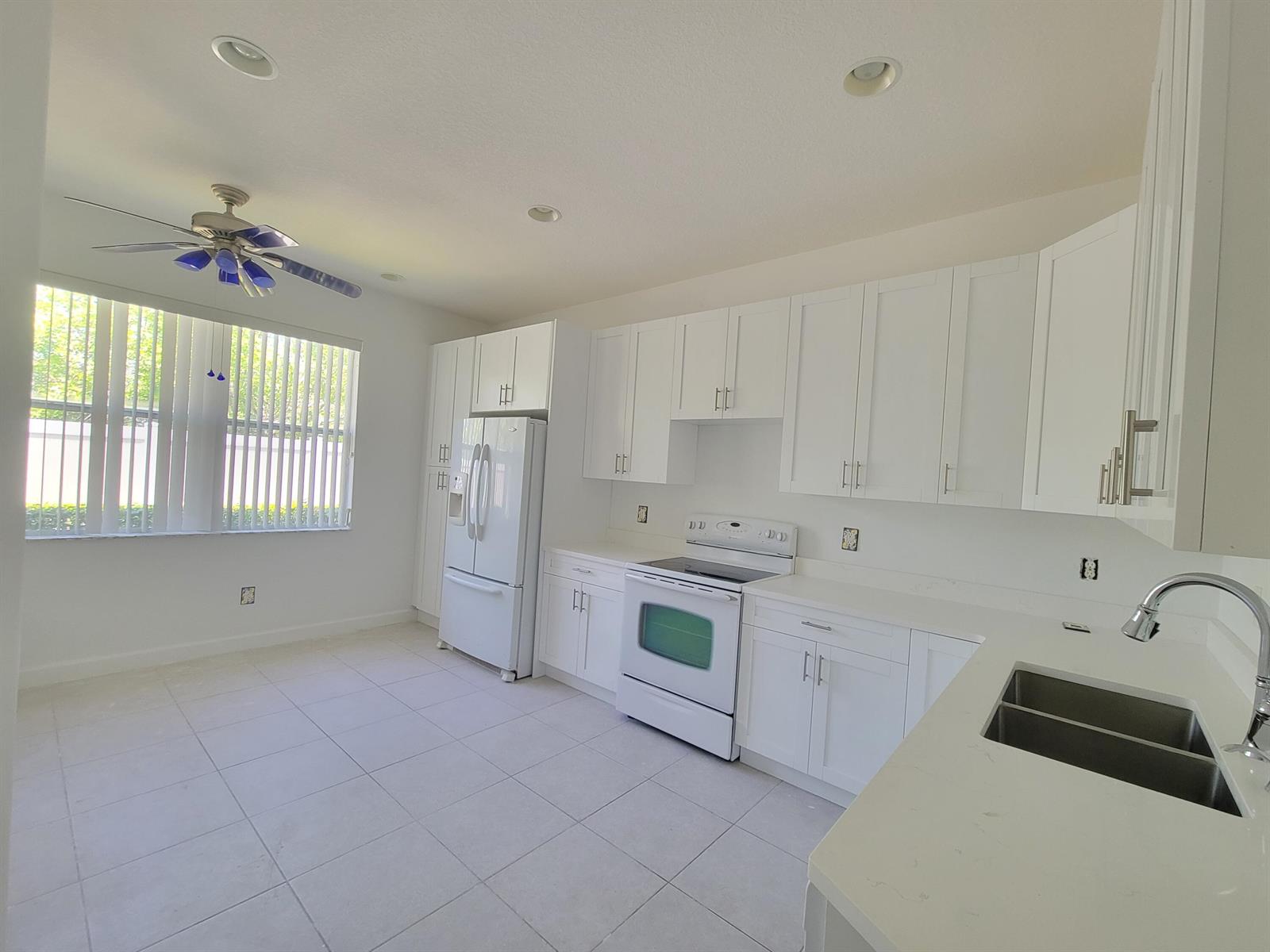 A white kitchen features white cabinets, stainless steel appliances, and a double-basin sink — 3103 Anthem Way, Vero Beach FL 32966, VERO BEACH, FL