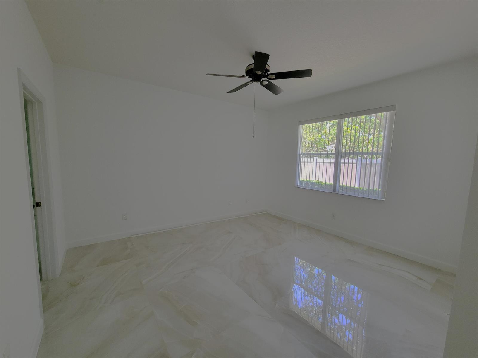 An empty bedroom features white walls, a ceiling fan, and polished marble-look tile flooring — 3103 Anthem Way, Vero Beach FL 32966, VERO BEACH, FL