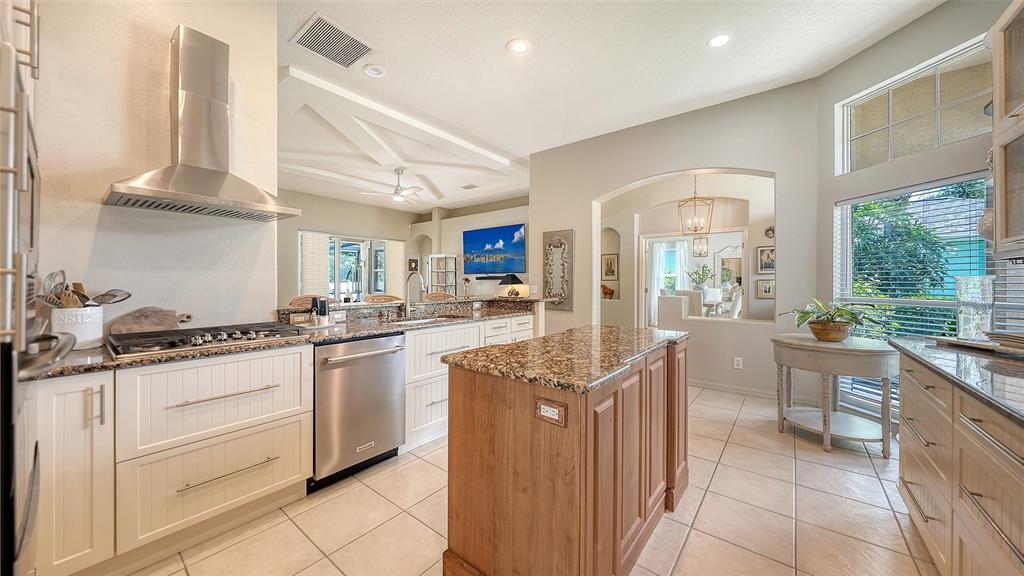 A kitchen features white cabinetry, granite countertops, a wooden island, and stainless steel appliances — 5122 CREEKSIDE TRAIL, SARASOTA, FL