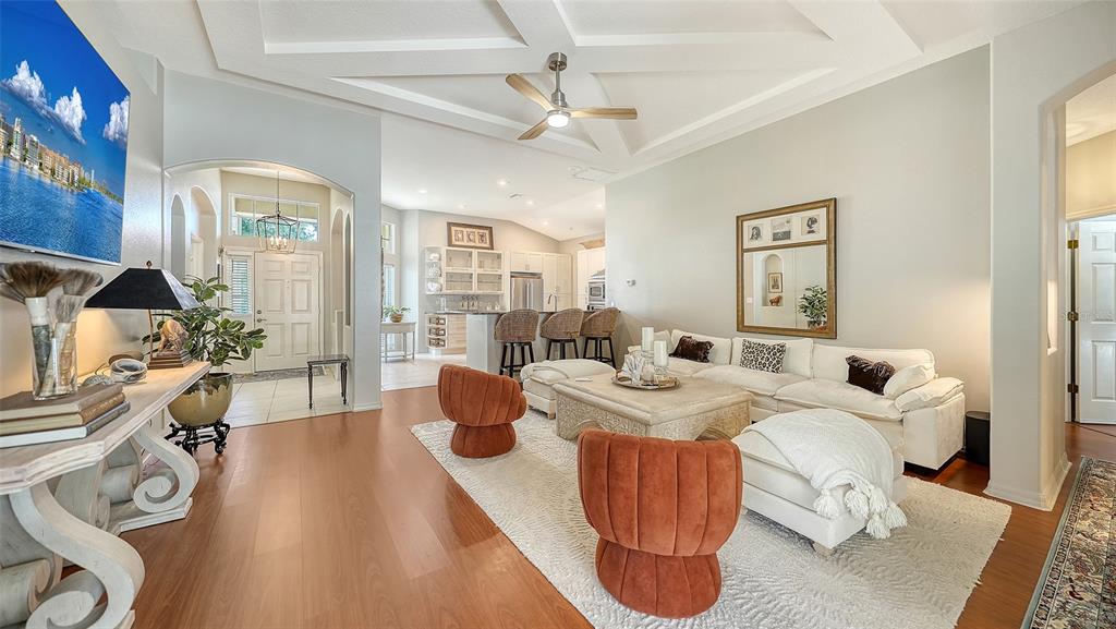 A living room with light wood floors, a white sectional, and two rust-colored accent chairs — 5122 CREEKSIDE TRAIL, SARASOTA, FL