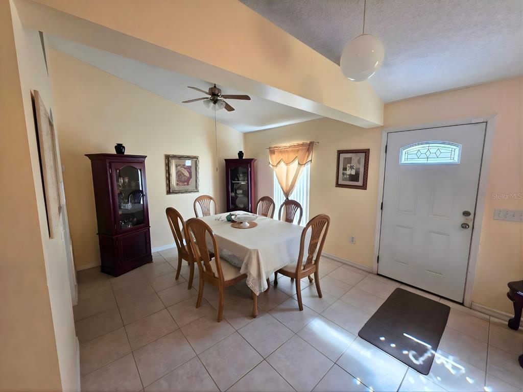 A dining room features tile flooring, a table with six chairs, and two dark wood cabinets — 907 STOCKPORT DRIVE, KISSIMMEE, FL