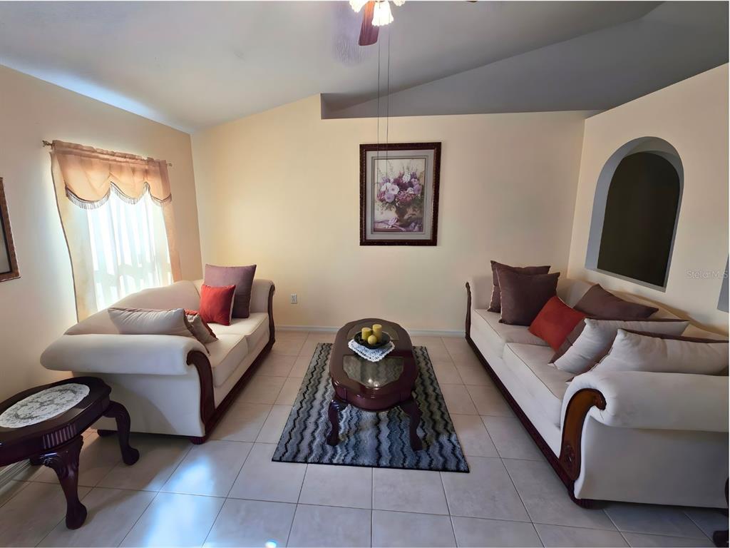 A living room features two cream-colored sofas, a coffee table, and a patterned area rug — 907 STOCKPORT DRIVE, KISSIMMEE, FL
