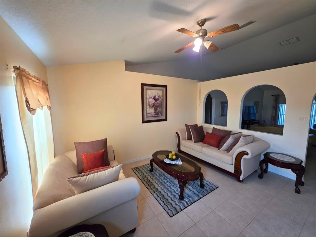 A living room features cream sofas, a coffee table, and arched wall cutouts — 907 STOCKPORT DRIVE, KISSIMMEE, FL