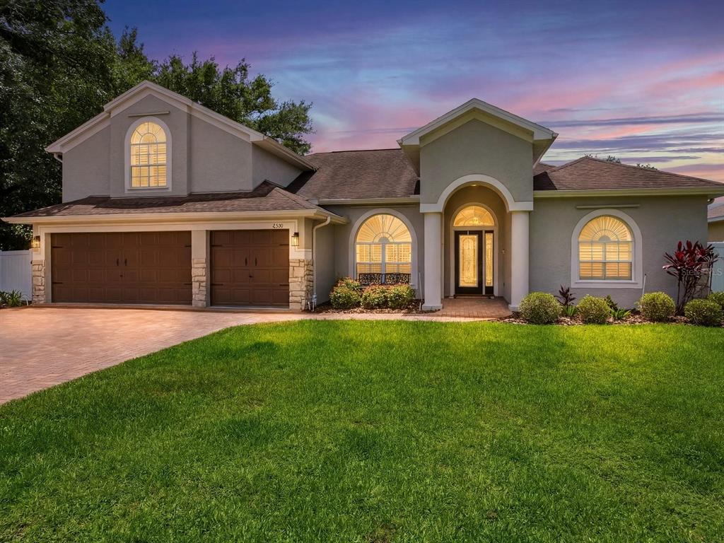 A two-story house with a brown two-car garage, arched windows, and a paved driveway — 6320 NIKKI LANE, TAMPA, FL