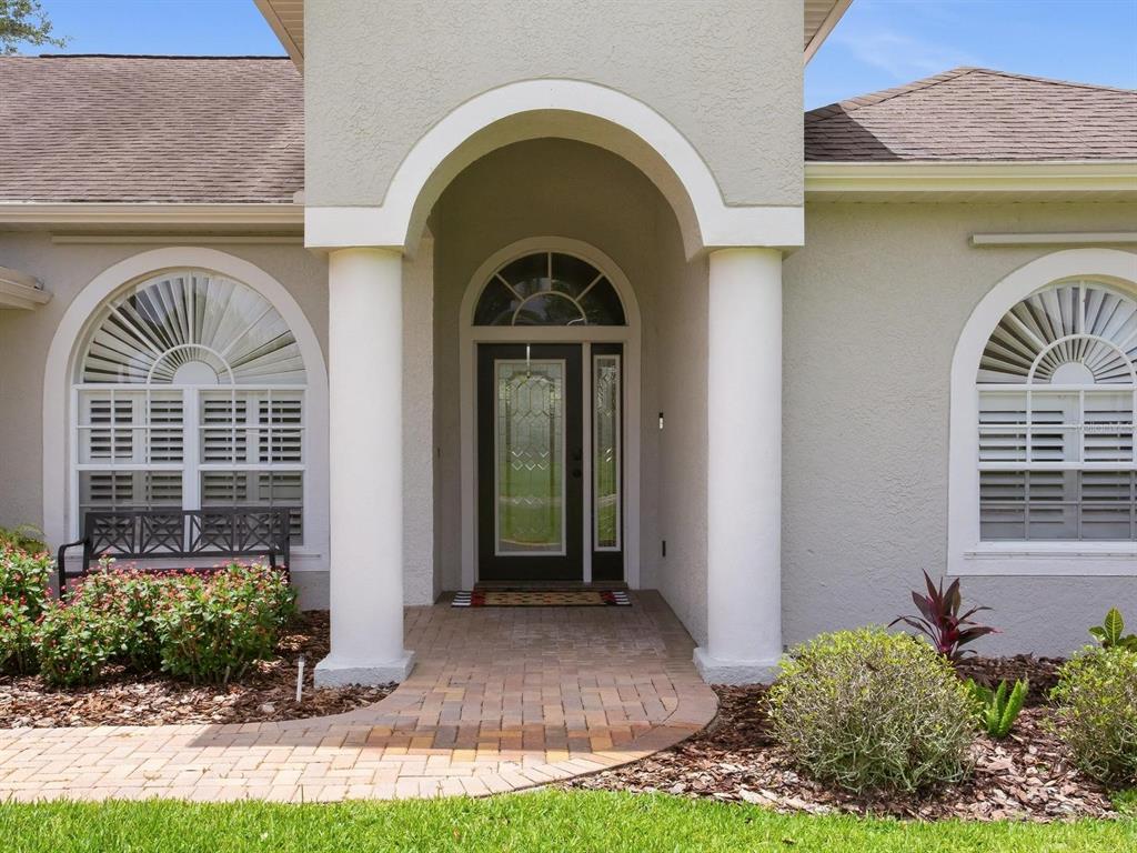The front entrance features a brick walkway, two white columns, and arched windows — 6320 NIKKI LANE, TAMPA, FL