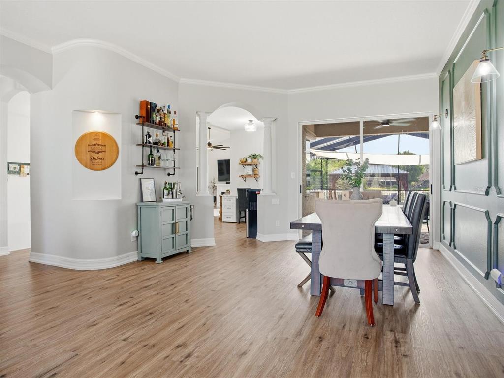 A dining room with wood-look flooring, a bar cabinet, and a view of a patio — 6320 NIKKI LANE, TAMPA, FL