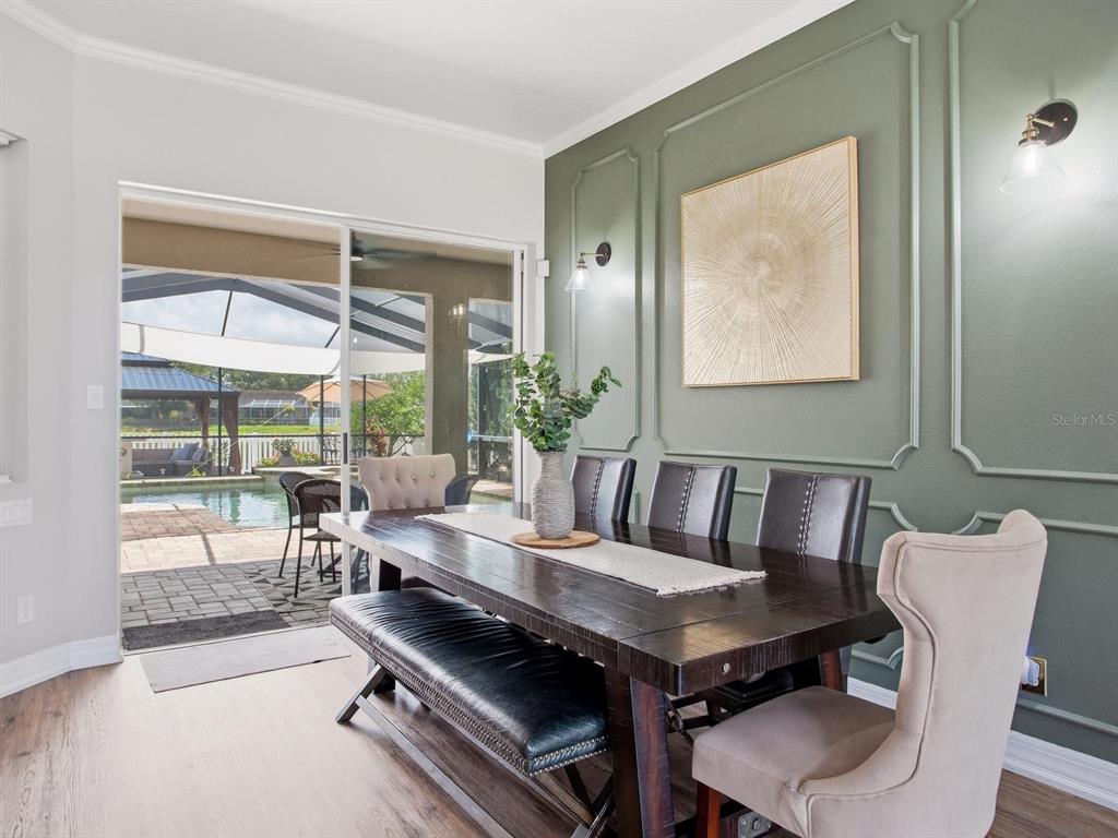 A dining room features a dark wood table, upholstered chairs, and a green paneled wall — 6320 NIKKI LANE, TAMPA, FL