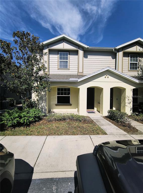 A two-story townhouse exterior features beige siding, a covered entryway, and a small front yard — 4754 CHATTERTON WAY, RIVERVIEW, FL