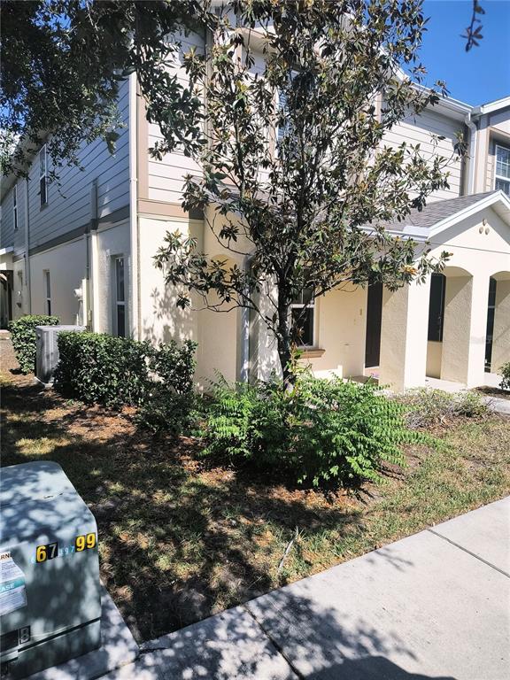 A two-story townhouse exterior with light-colored siding, a small front yard, and a utility box — 4754 CHATTERTON WAY, RIVERVIEW, FL