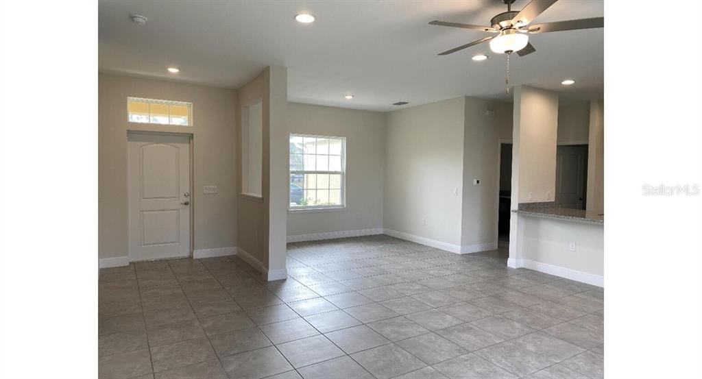 An open-concept living area features light-colored walls, tile flooring, a ceiling fan, and recessed lighting — 7050 BECKWITH AVENUE, NORTH PORT, FL