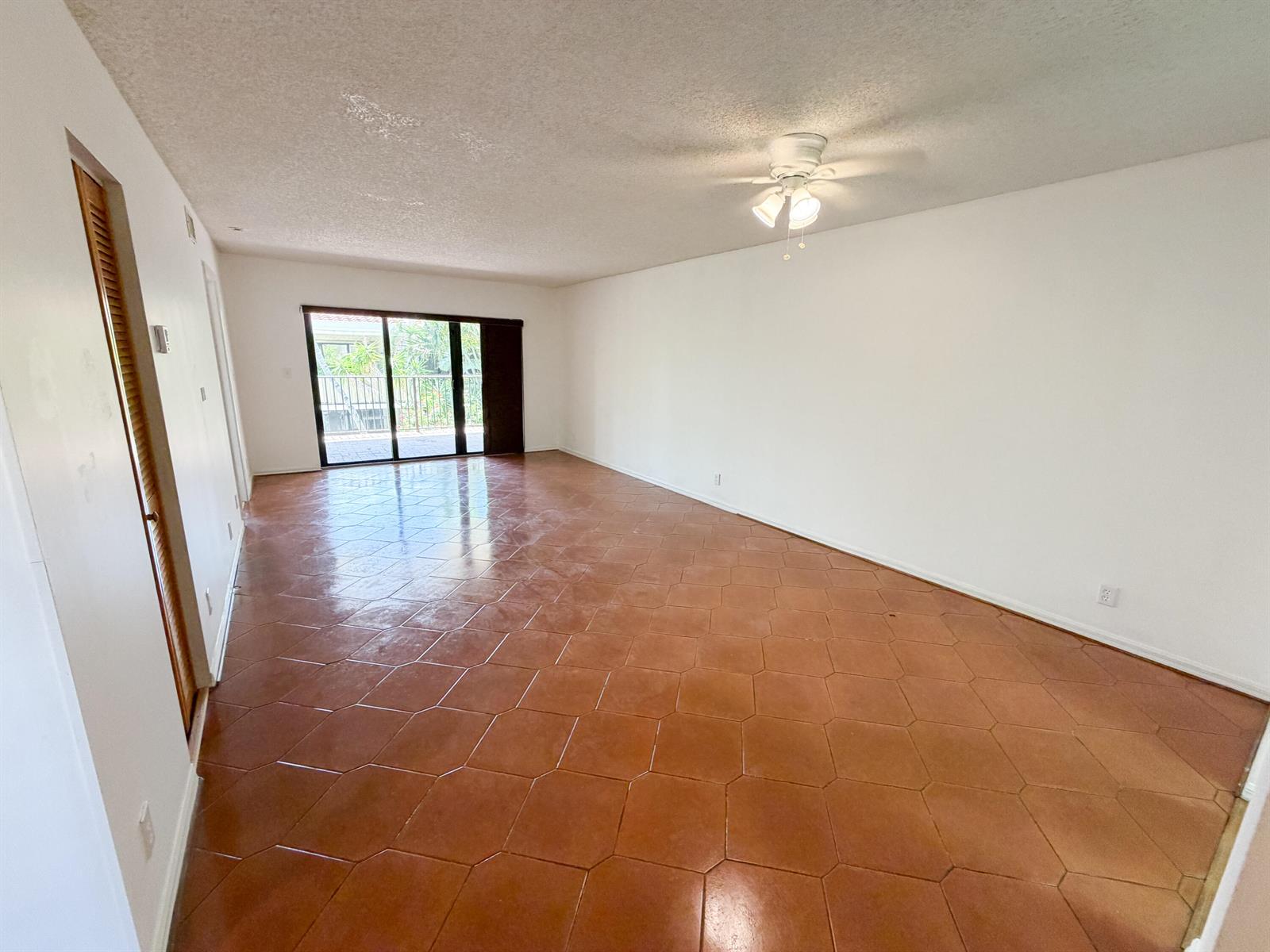 An empty living room features hexagonal terracotta floor tiles, white walls, and a ceiling fan — 241 SE 11th Avenue # 241a, Pompano Beach FL 33060, POMPANO BEACH, FL
