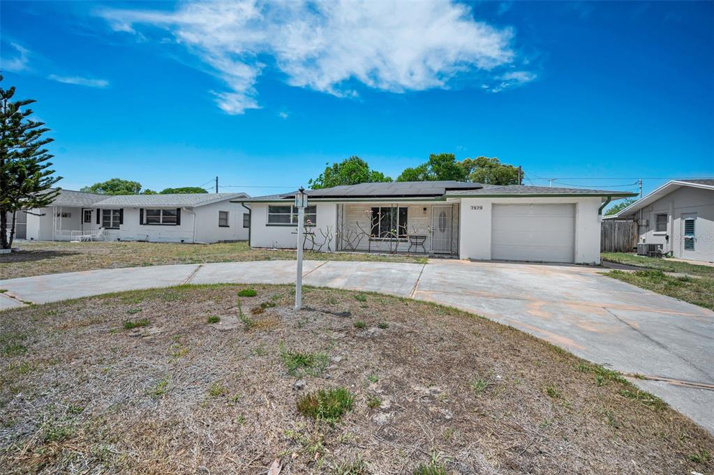 A single-story house with a concrete driveway, solar panels, and a one-car garage — 7529 REDCOAT AVENUE, PORT RICHEY, FL