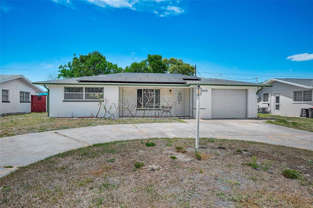 A single-story house with a white exterior, solar panels, and a concrete driveway — 7529 REDCOAT AVENUE, PORT RICHEY, FL