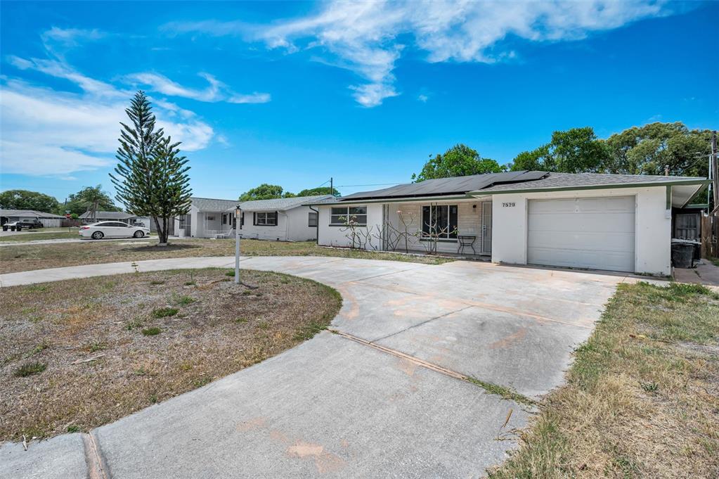 A single-story house with a white exterior, a garage, and a large concrete driveway — 7529 REDCOAT AVENUE, PORT RICHEY, FL