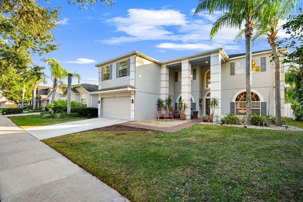A two-story suburban house with a light-colored stucco exterior, a two-car garage, and palm trees — 1349 CASTLEPORT ROAD, WINTER GARDEN, FL