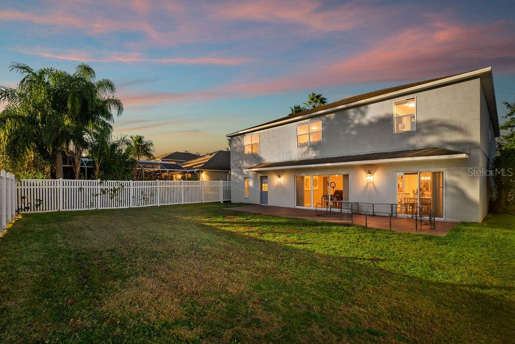 The backyard of a two-story house features a white fence, a patio, and green grass — 1349 CASTLEPORT ROAD, WINTER GARDEN, FL