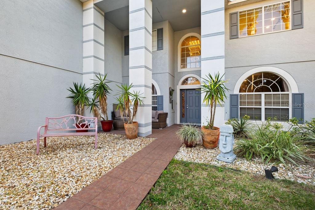 The exterior of a two-story home features a covered entryway with a pink bench — 1349 CASTLEPORT ROAD, WINTER GARDEN, FL