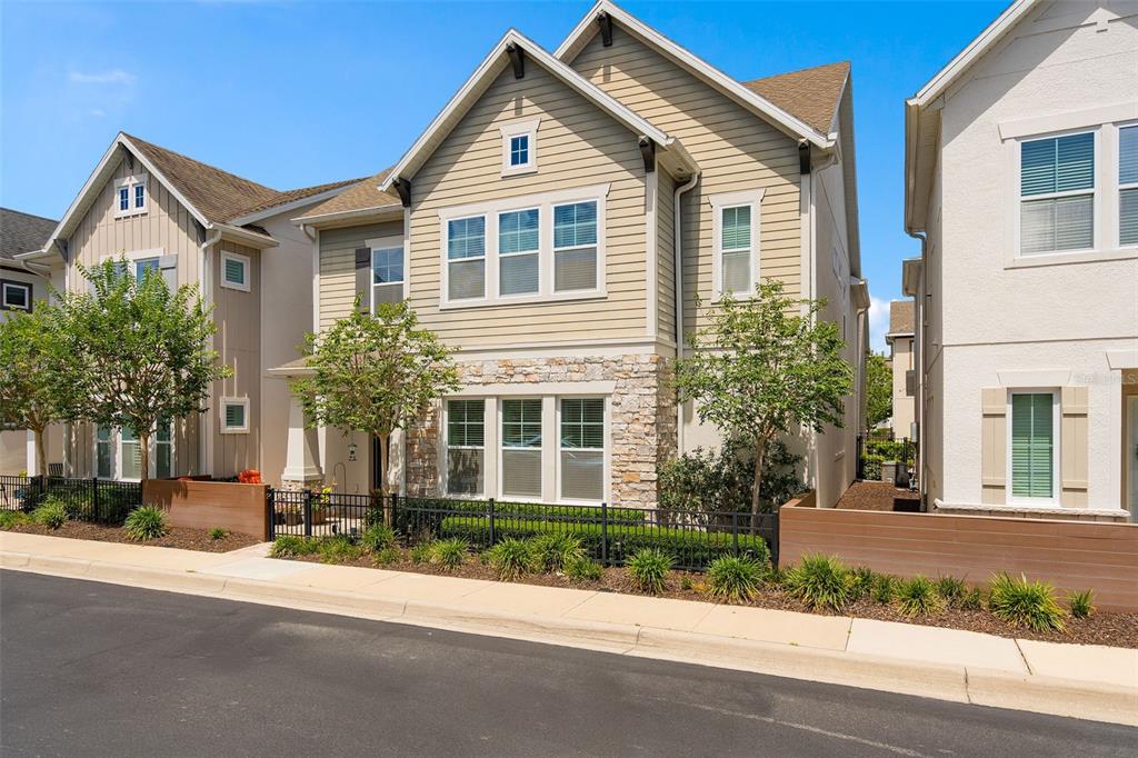 A two-story house with tan siding, stone accents, and a black metal fence — 344 WHEELHOUSE LANE, LAKE MARY, FL