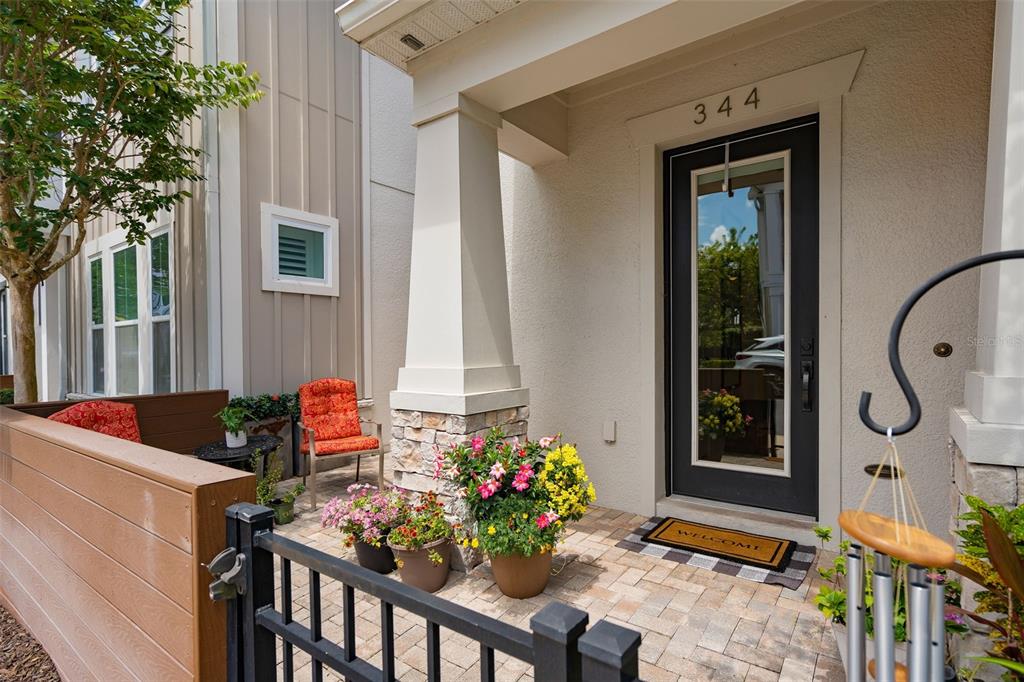 A paved front porch features a dark door, stone-based pillar, and potted flowers — 344 WHEELHOUSE LANE, LAKE MARY, FL