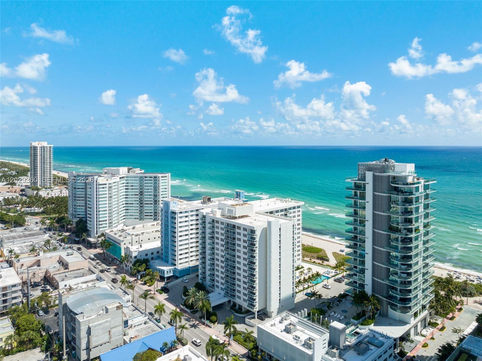 An aerial view shows multiple high-rise residential buildings along a sandy beach and ocean — 6917 Collins Ave # 607, Miami Beach FL 33141, MIAMI BEACH, FL