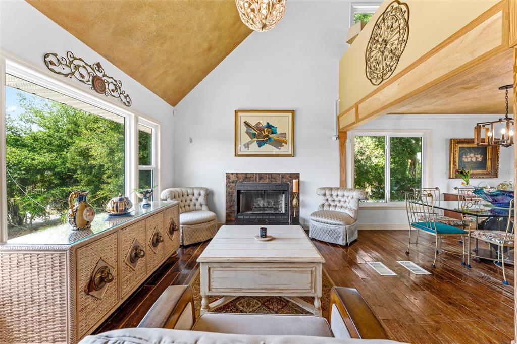 A living room with a vaulted ceiling, fireplace, white coffee table, and hardwood floors — 13332 SUBURBAN TERRACE, WINTER GARDEN, FL