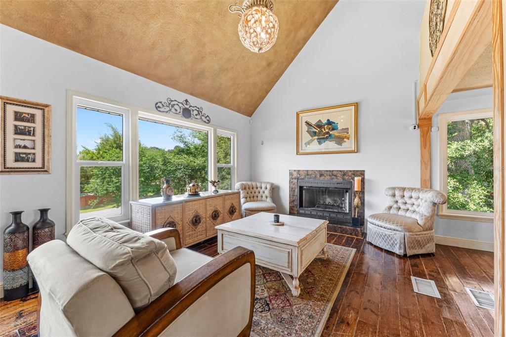 A living room features a vaulted ceiling, fireplace, hardwood floors, and large windows — 13332 SUBURBAN TERRACE, WINTER GARDEN, FL
