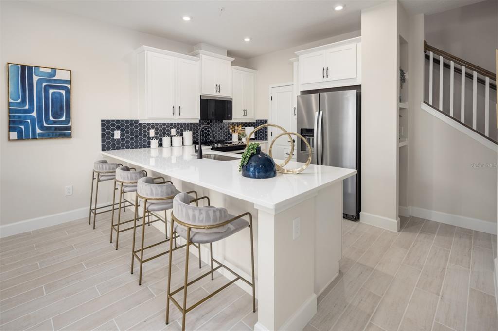 A kitchen features white cabinets, a dark hexagonal tile backsplash, and a white island — 2812 CAMELLIA FLOWER STREET, APOPKA, FL