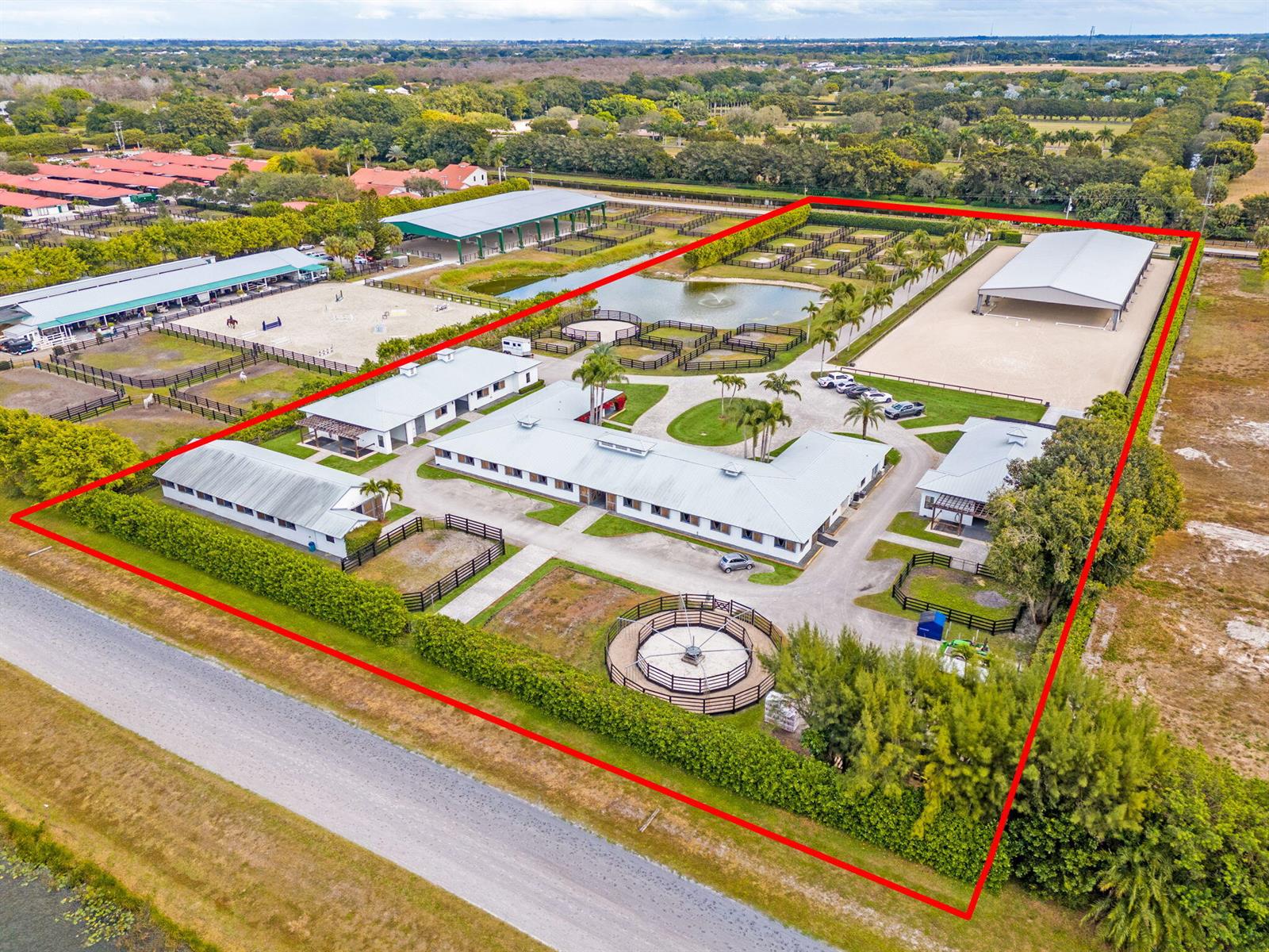 An aerial view shows a horse farm with stables, riding arenas, and a round pen — 13155 Southfields Road, Wellington FL 33414, WELLINGTON, FL
