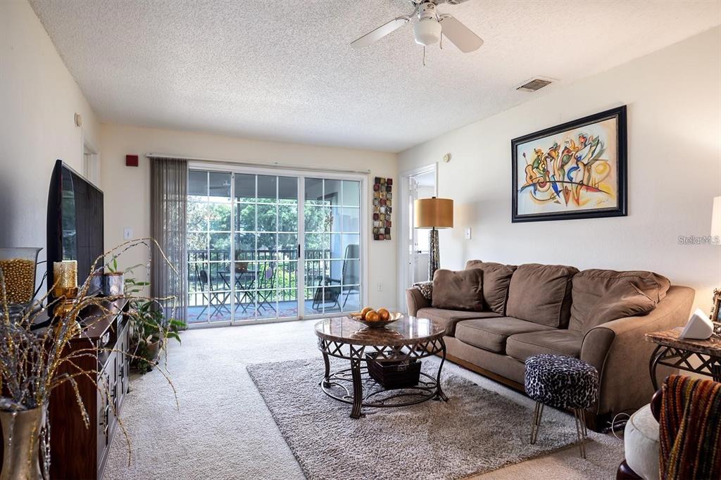 A living room features a brown sofa, a round coffee table, and a sliding glass door — 3206 CLUBSIDE DRIVE UNIT 3206, LONGWOOD, FL