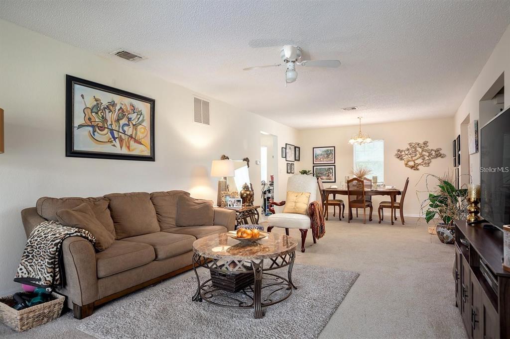 A living room with a brown sofa, a round coffee table, and a dining area — 3206 CLUBSIDE DRIVE UNIT 3206, LONGWOOD, FL