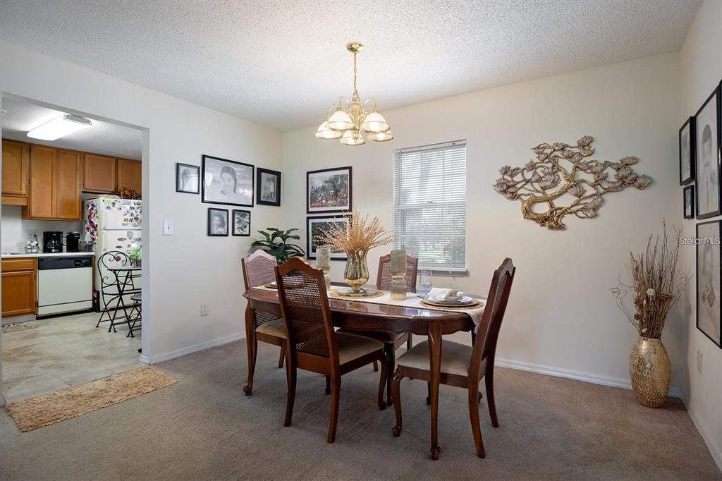 A dining room with a wooden table, four chairs, a chandelier, and wall decor — 3206 CLUBSIDE DRIVE UNIT 3206, LONGWOOD, FL
