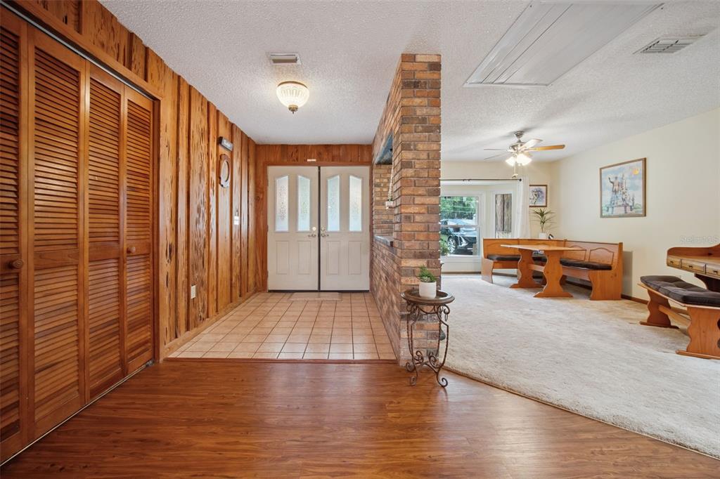 An entryway with wood-paneled walls and tile flooring leads to a carpeted dining area — 7232 E TURNER CAMP ROAD, INVERNESS, FL