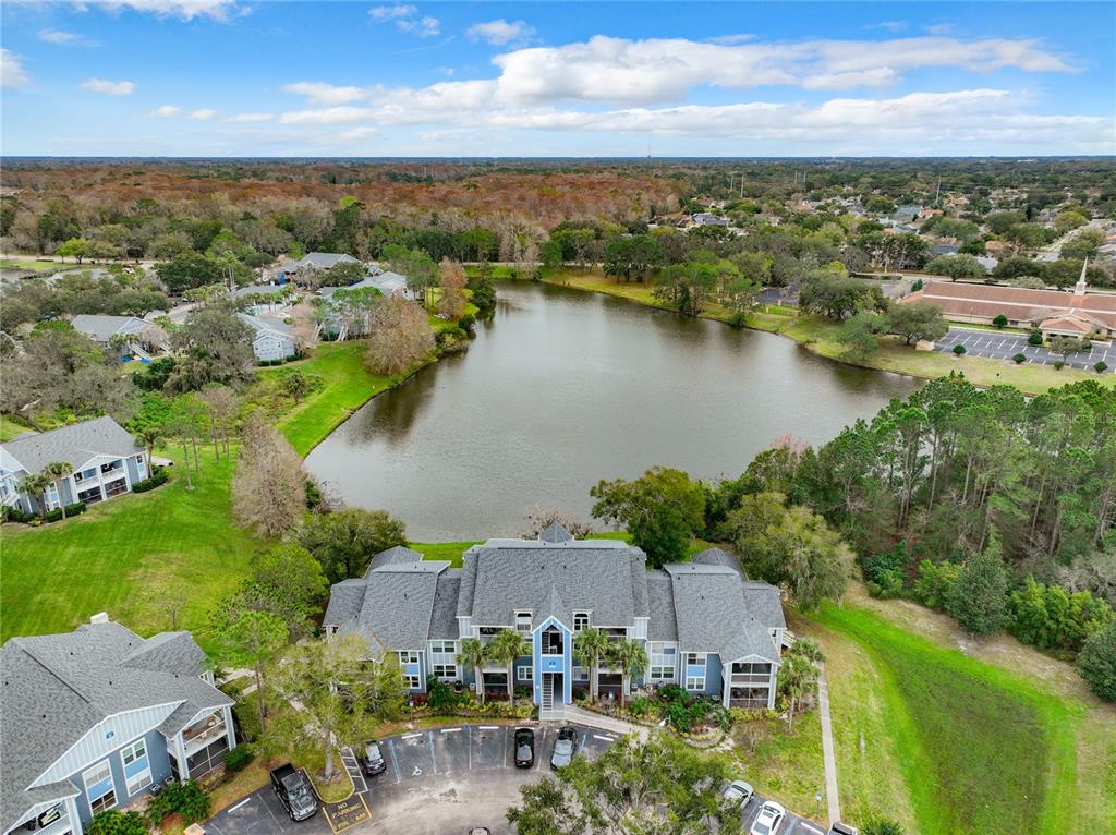 An aerial view shows a multi-story apartment building situated next to a lake — 2612 GRASSY POINT DRIVE UNIT 102, LAKE MARY, FL