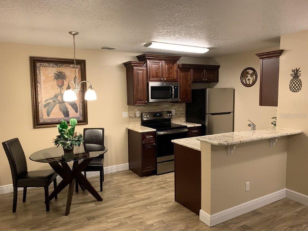 A kitchen with dark wood cabinets, granite countertops, and an adjacent dining area — 2612 GRASSY POINT DRIVE UNIT 102, LAKE MARY, FL