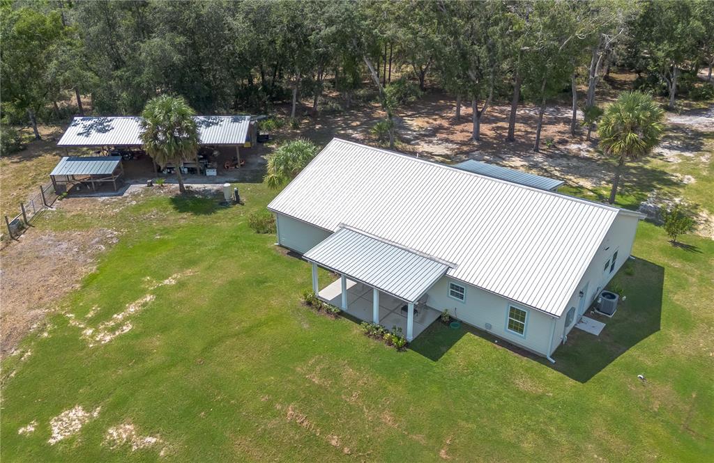 An aerial view shows a light-colored house with a metal roof and a detached carport — 14042 NE 110TH STREET, FORT MC COY, FL
