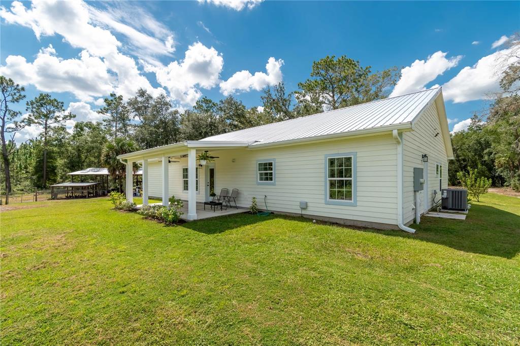 A light yellow house with a metal roof and a covered porch sits on grass — 14042 NE 110TH STREET, FORT MC COY, FL