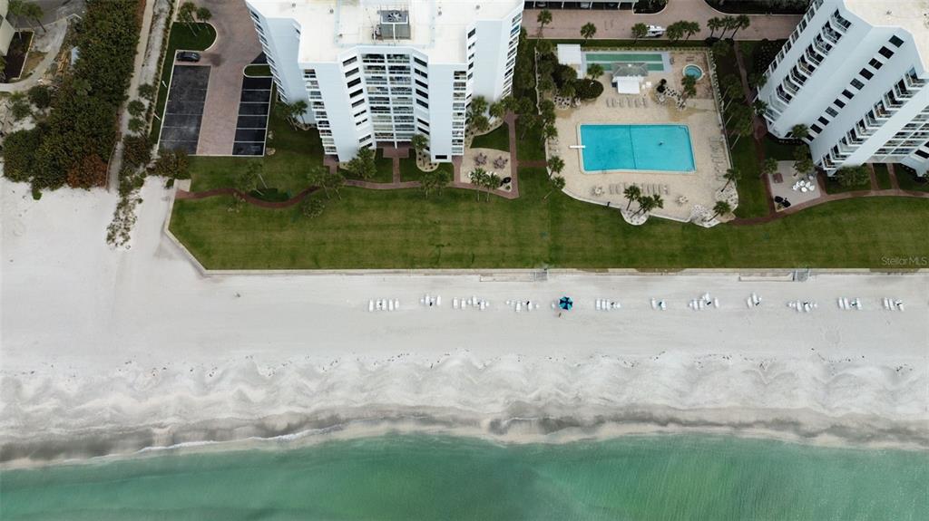 An aerial view shows two beachfront apartment buildings with a pool and a sandy beach — 1050 LONGBOAT CLUB ROAD UNIT 506, LONGBOAT KEY, FL