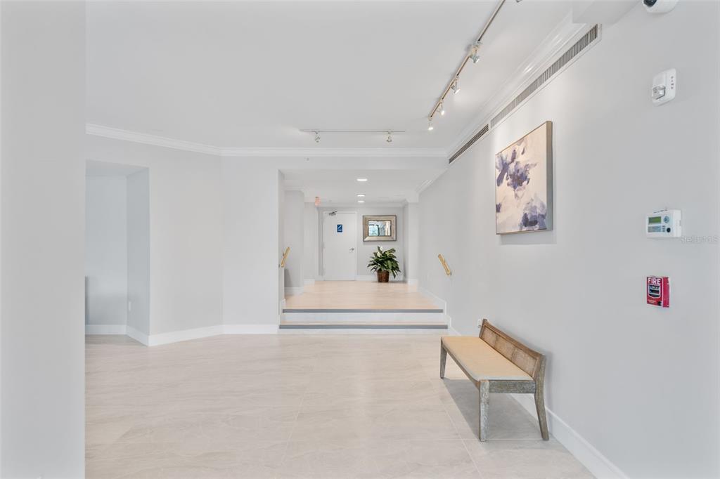 A bright hallway features light tile flooring, a wooden bench, and a raised entryway — 1050 LONGBOAT CLUB ROAD UNIT 506, LONGBOAT KEY, FL