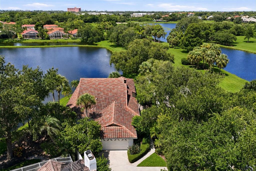 An aerial view of a house with a tiled roof surrounded by trees and lakes — 4300 CAMINO MADERA, SARASOTA, FL